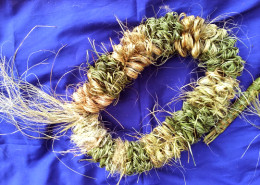 Densely woven circular item on a purple cloth.