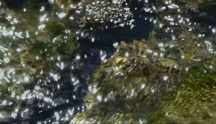 A still image of shimmering surface of moving river water.